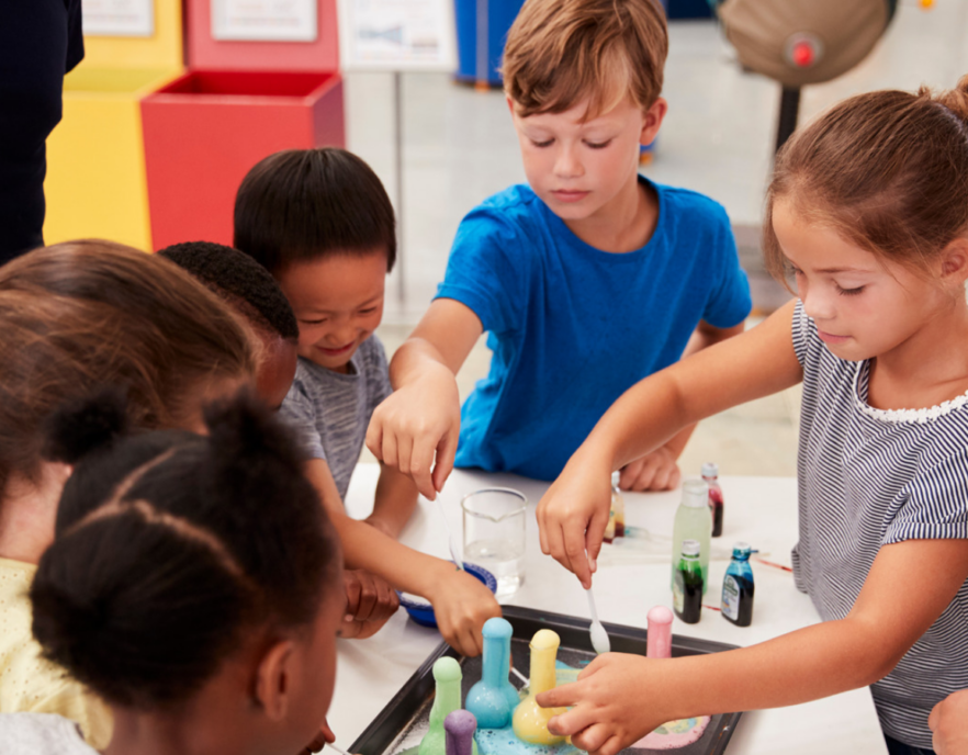 A group of children gathered around a table participating in a hands-on science activity.